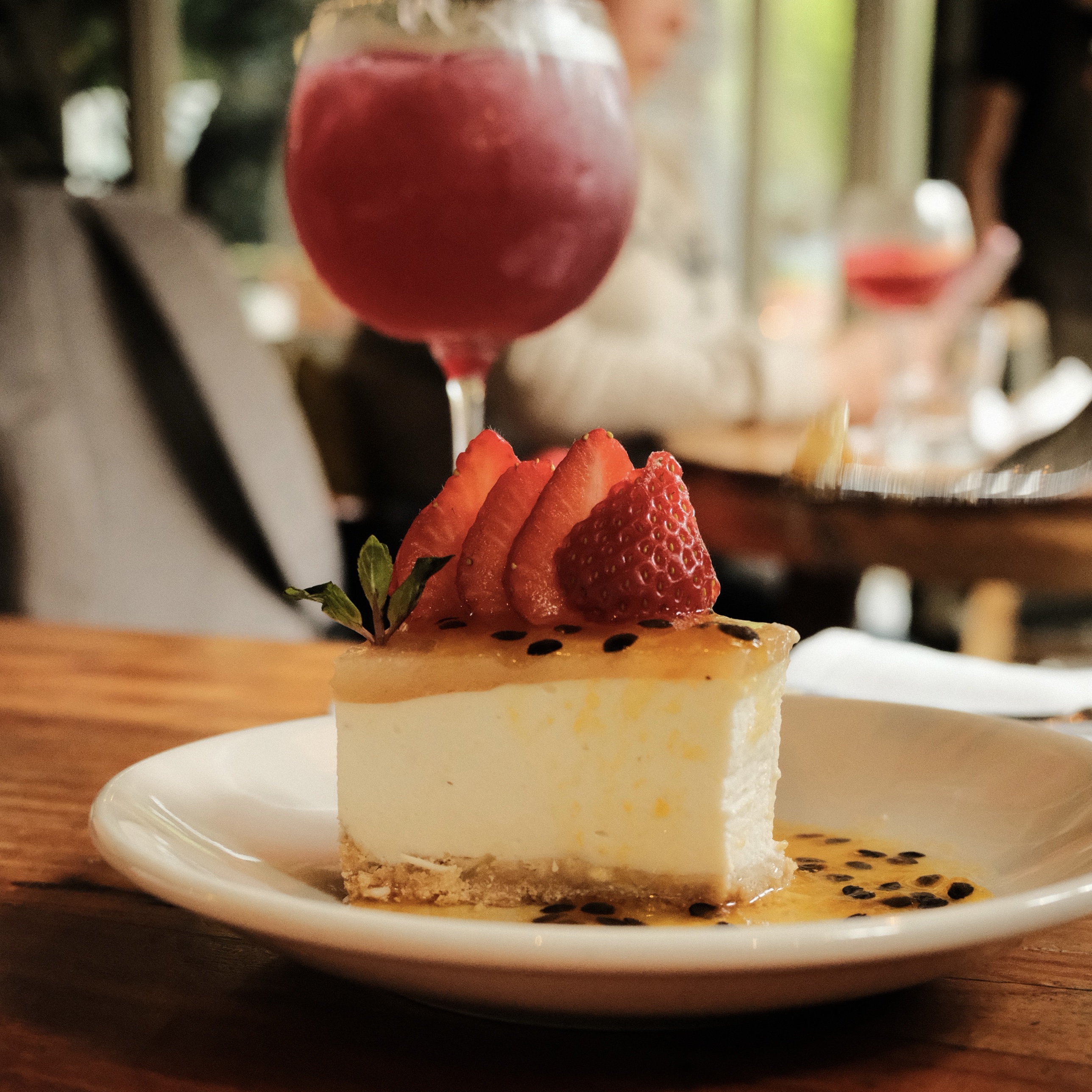 Passion fruit cheesecake with strawberries and a cocktail