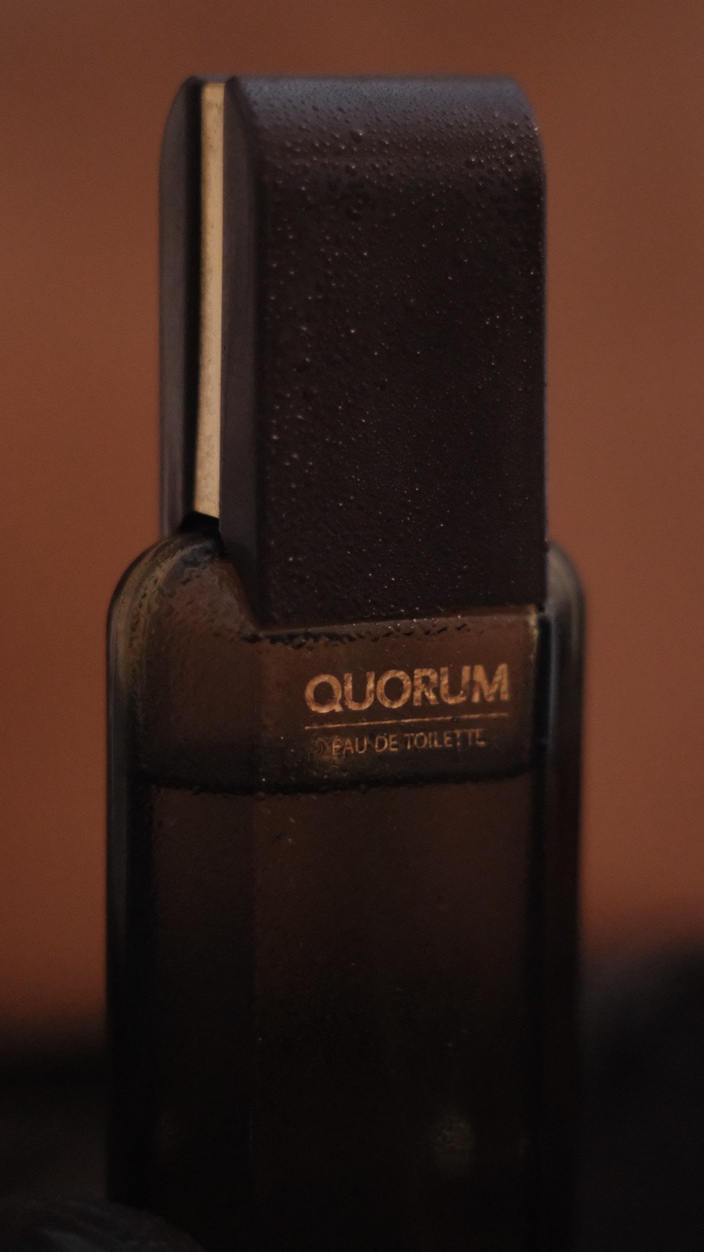 Quorum eau de toilette bottle with condensation, warm terracotta backdrop